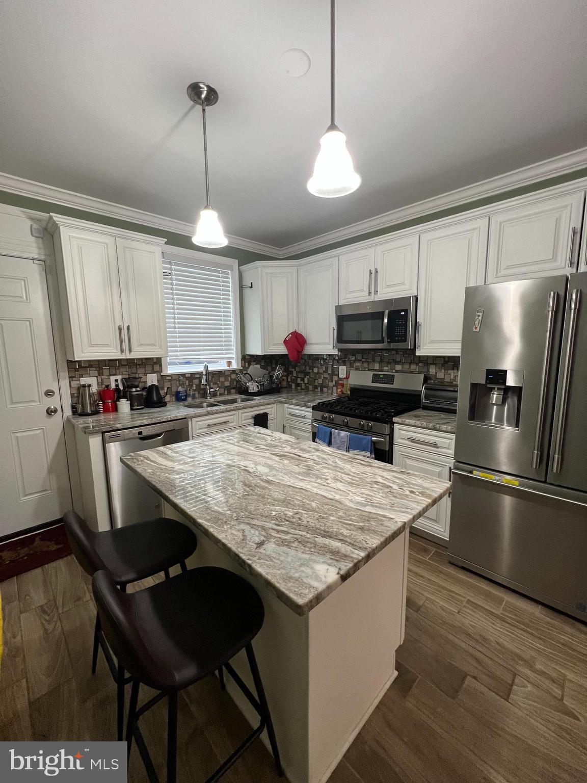 3319 Noble Street Baltimore, MD 21224 - Photo 10 of 31 a kitchen with kitchen island granite countertop a stove a sink a refrigerator wooden floor and a window