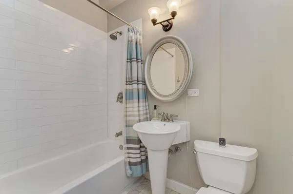 a bathroom with a toilet sink mirror vanity and bathtub