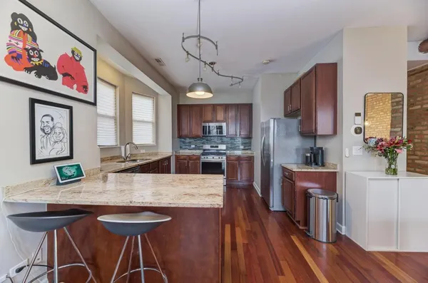 a kitchen with stainless steel appliances granite countertop a stove top oven a refrigerator a sink and dishwasher with wooden floor