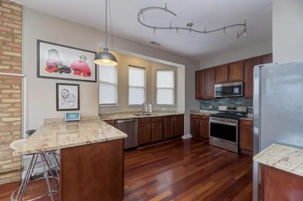 a kitchen with stainless steel appliances granite countertop a stove top oven a sink dishwasher a dining table and chairs with wooden floor