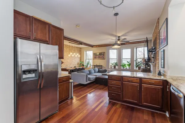 a kitchen with stainless steel appliances granite countertop a refrigerator a sink dishwasher a stove and white cabinets with wooden floor
