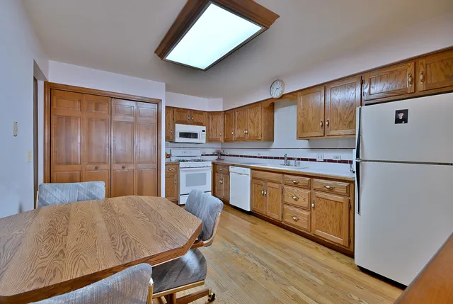 a kitchen with stainless steel appliances granite countertop a refrigerator a stove and a sink with wooden floors