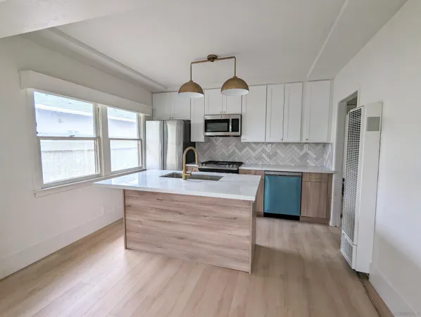 a kitchen with kitchen island a large counter top space stainless steel appliances and a window
