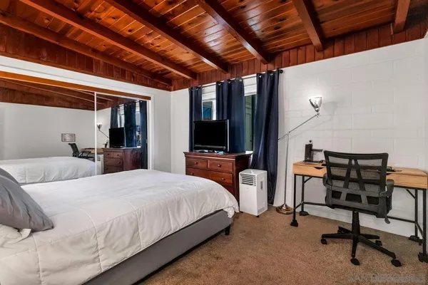 a bedroom with a bed a desk and chair with the view of bathroom