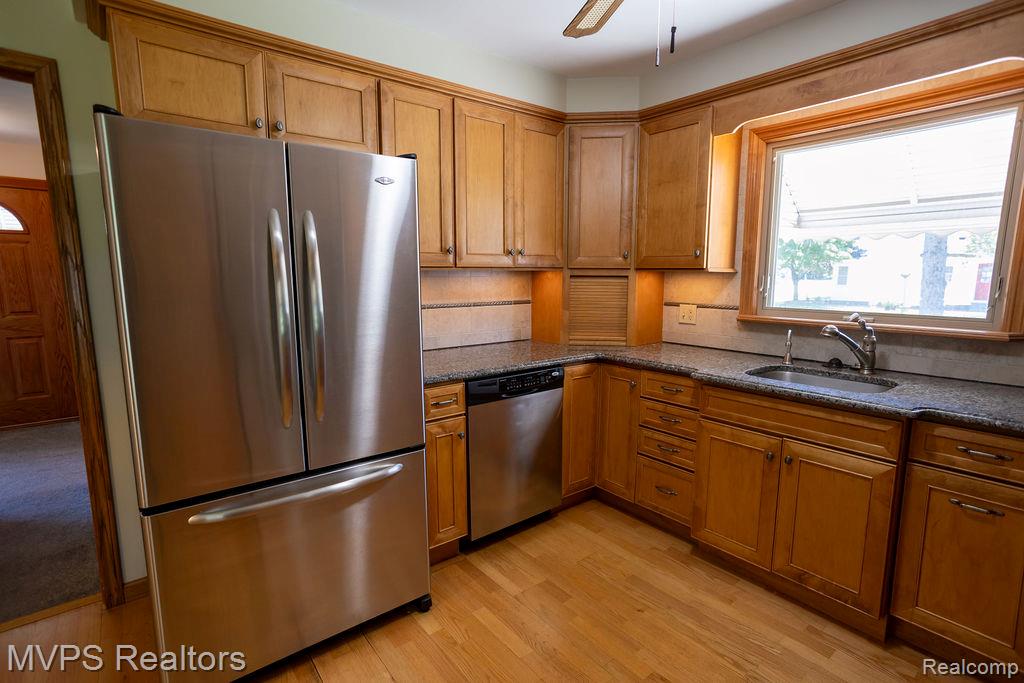 33033 Edgegrove Road Fraser, MI 48026 - Photo 10 of 20 Kitchen featuring wood-finish cabinetry, granite-style countertops, stainless steel appliances, hardwood flooring, and a large window above the sink