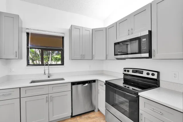 a kitchen with cabinets stainless steel appliances a sink and a window