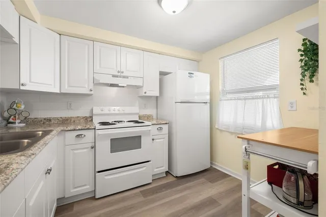 a kitchen with granite countertop white cabinets and white appliances