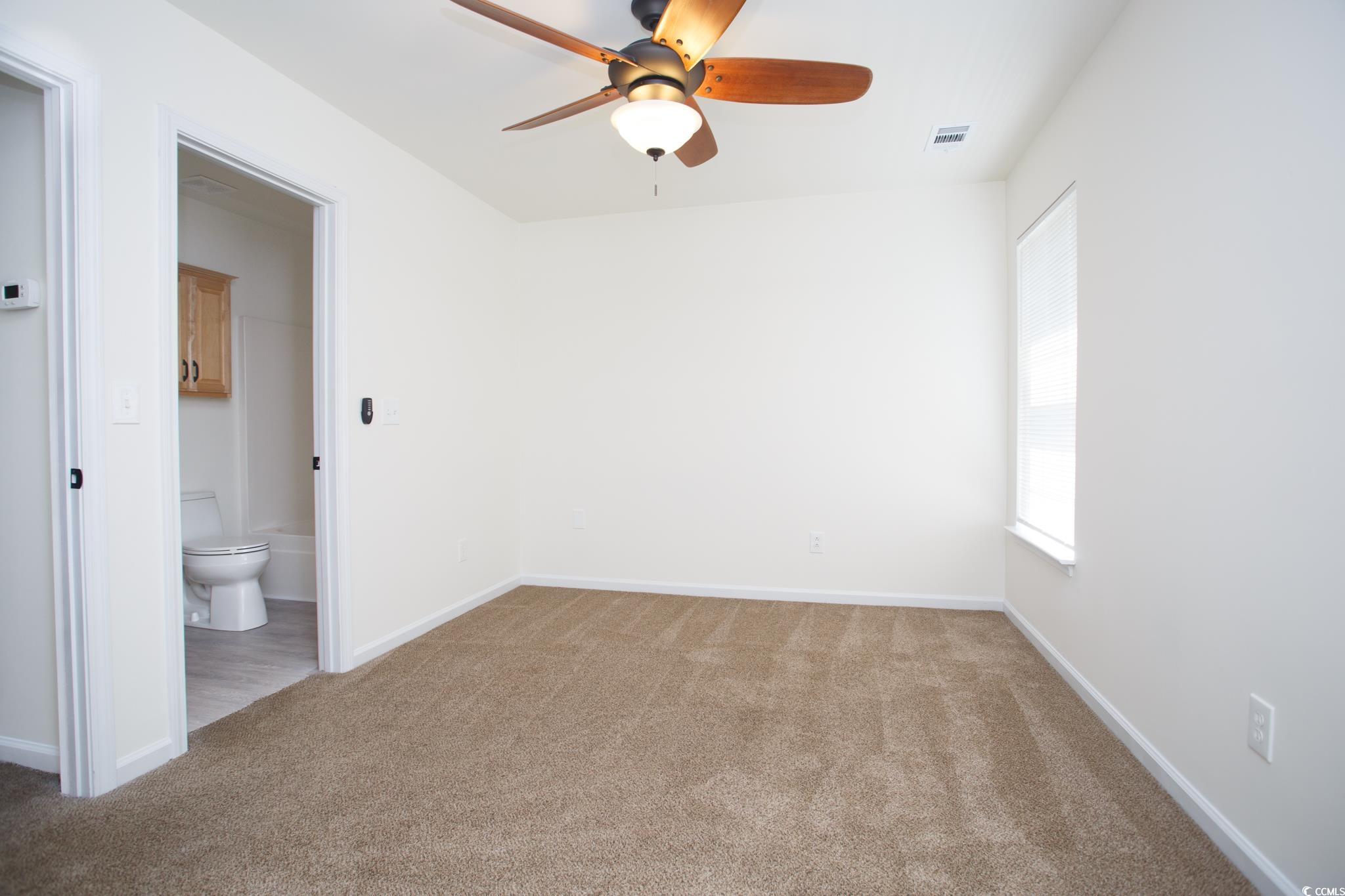 116 Barnacle Lane, Unit 1 Little River, SC 29566 - Photo 13 of 27 Unfurnished bedroom featuring light colored carpet, a ceiling fan, and connected bathroom