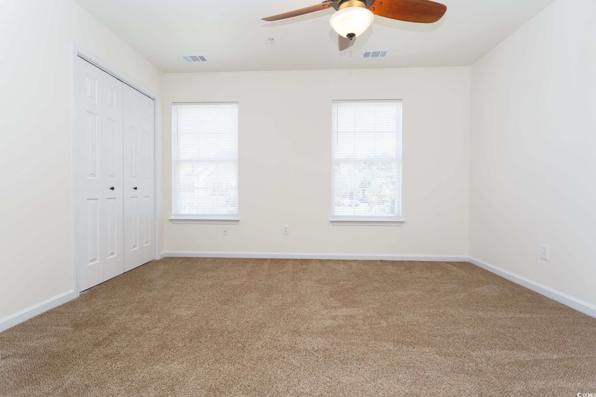 116 Barnacle Lane, Unit 1 Little River, SC 29566 - Photo 15 of 27 Unfurnished bedroom featuring multiple windows, carpet, a closet, and ceiling fan