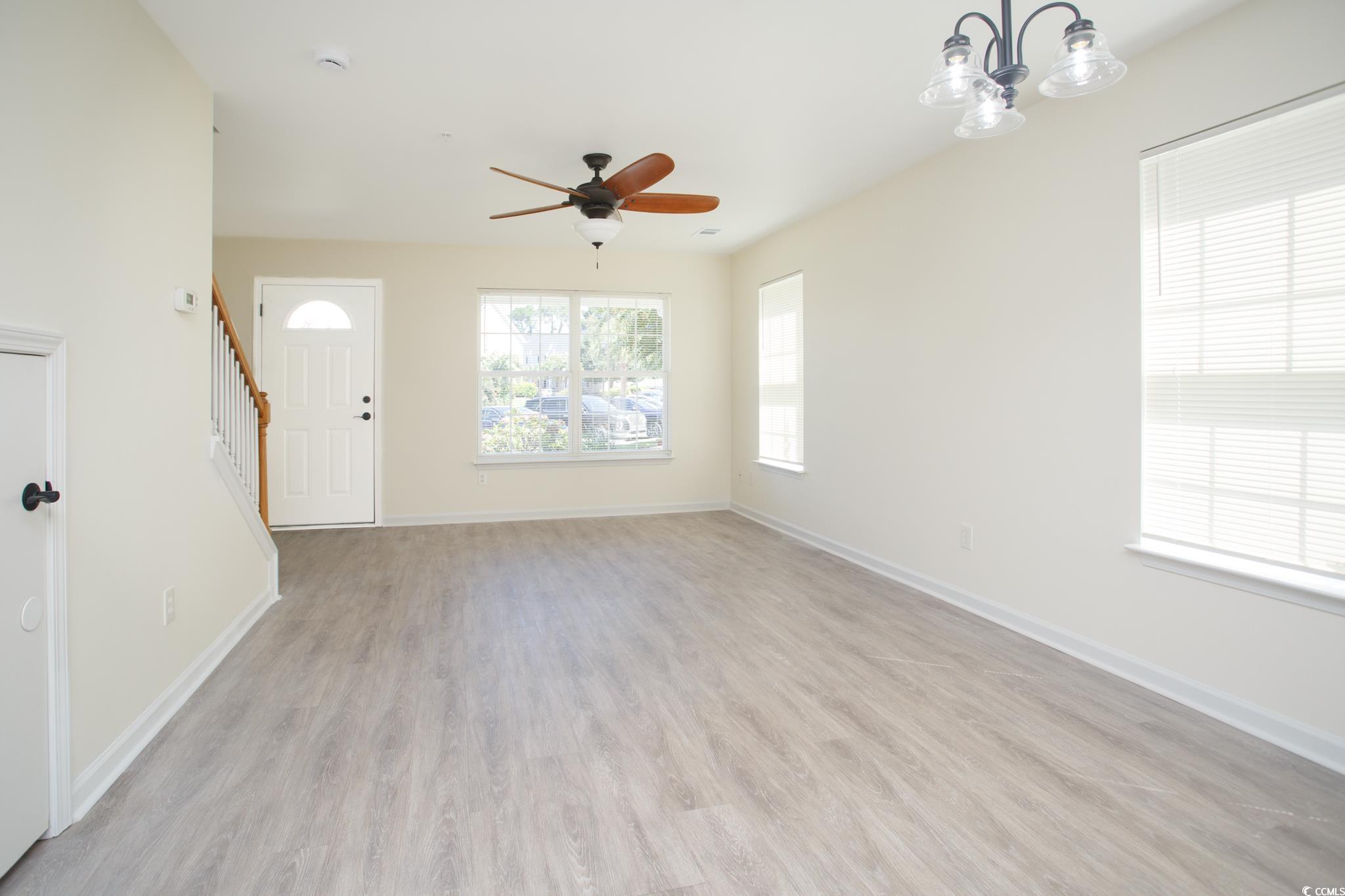 116 Barnacle Lane, Unit 1 Little River, SC 29566 - Photo 6 of 27 Unfurnished living room featuring light wood-style flooring, stairs, ceiling fan, and a chandelier