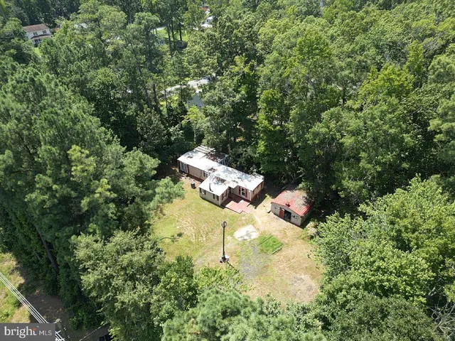 an aerial view of residential house with outdoor space and trees all around