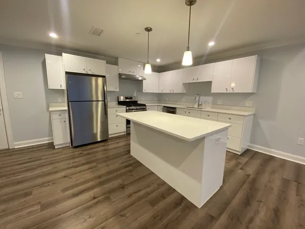 a kitchen with a refrigerator a sink and wooden floor