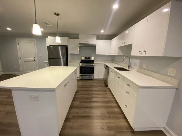 a large kitchen with stainless steel appliances a large kitchen island a stove a refrigerator a oven and a sink with large countertops