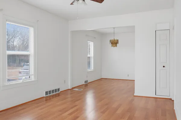 a view of an empty room with wooden floor and a window