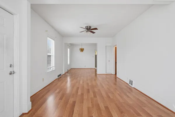 an empty room with wooden floor and ceiling fan