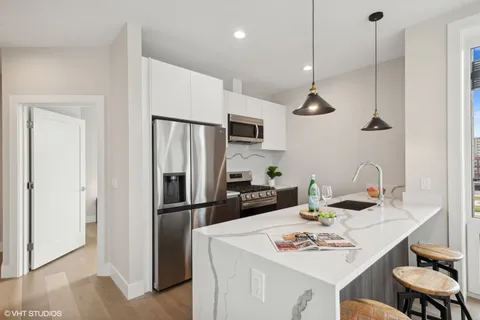 a kitchen with stainless steel appliances kitchen island granite countertop a sink and a living room view