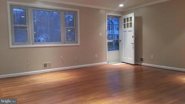 a view of an empty room with wooden floor and a window
