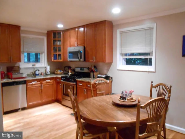 a kitchen with stainless steel appliances granite countertop a stove a sink a dining table and chairs