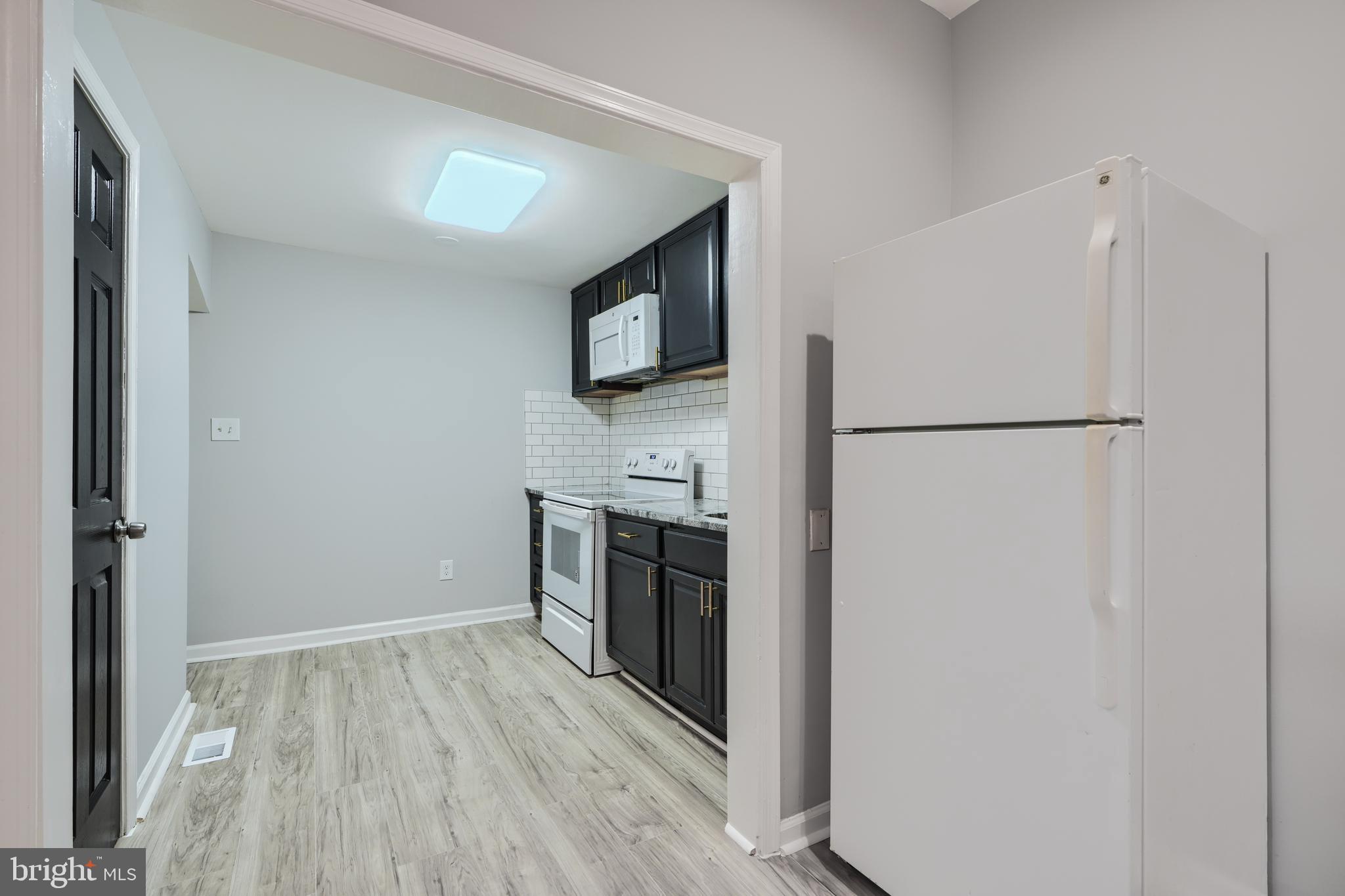 3014 Hamilton Avenue, Unit 1 Baltimore, MD 21214 - Photo 11 of 36 a kitchen with a refrigerator a stove top oven and wooden floor