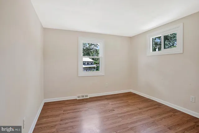 a view of an empty room with wooden floor and a bathroom