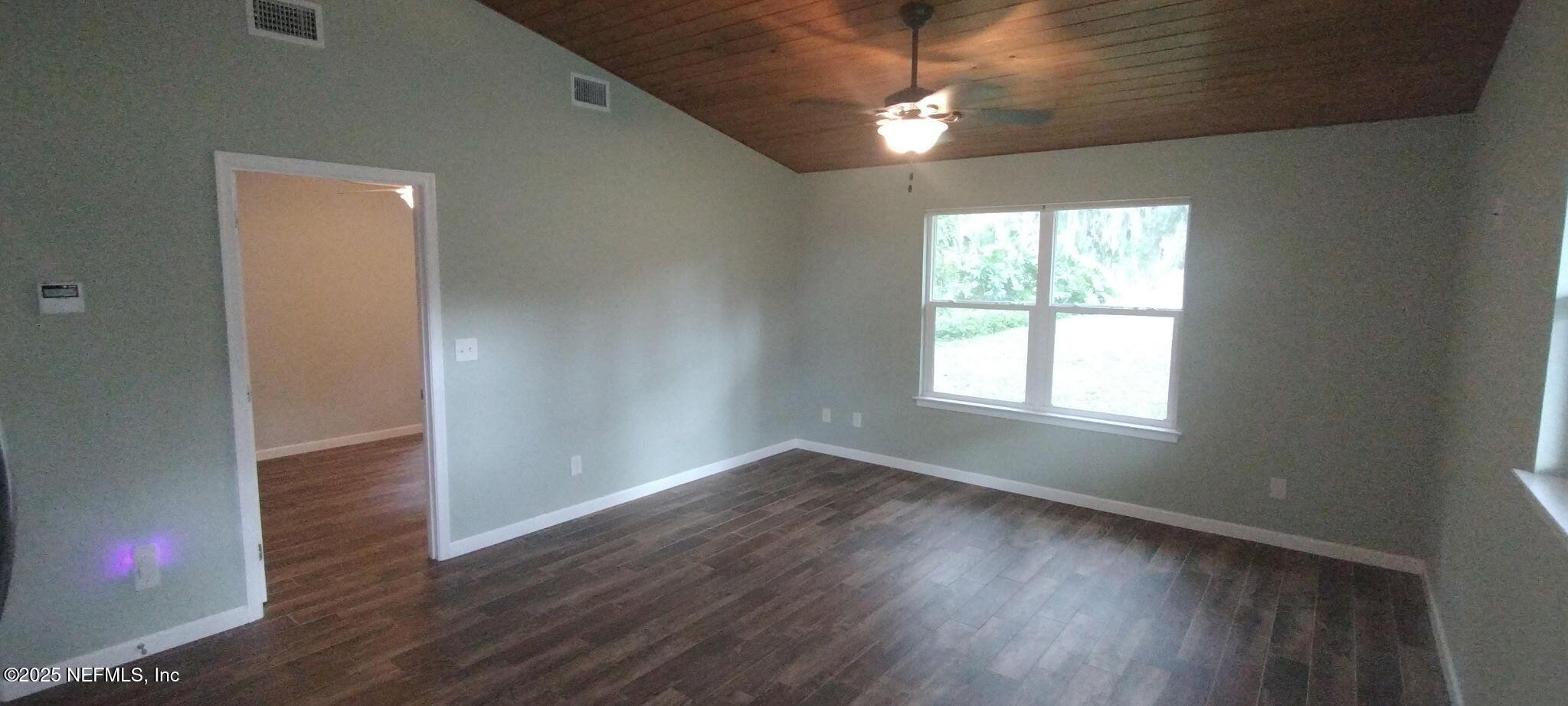 1521 County Road 309, Unit 1 Georgetown, FL 32139 - Photo 9 of 10 an empty room with wooden floor chandelier fan and windows