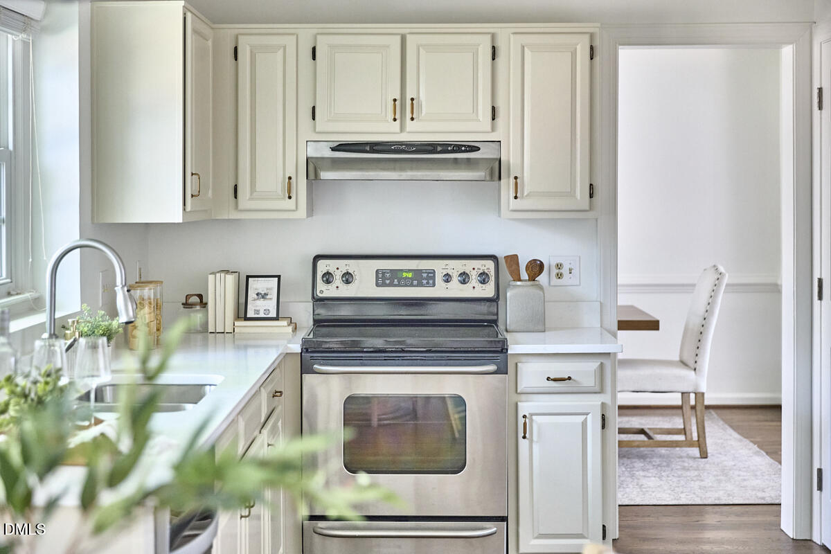 5220 Oakbrook Drive Durham, NC 27713 - Photo 11 of 38 a kitchen with granite countertop a stove a sink and white cabinets