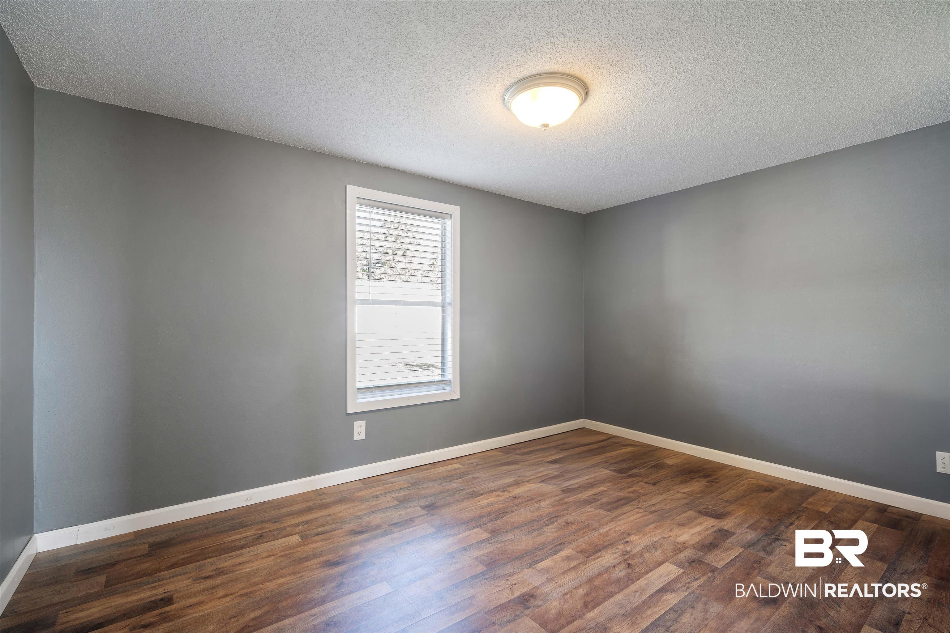 9011 Wilmer Georgetown Road Wilmer, AL 36587 - Photo 17 of 34 Spare room with baseboards, a textured ceiling, and dark wood-style flooring
