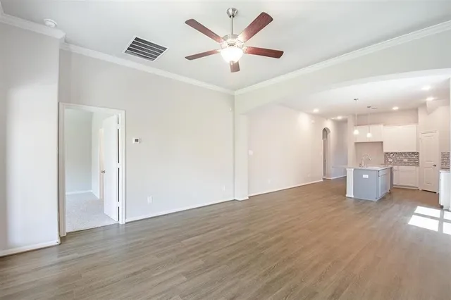 a view of a livingroom with a kitchen island wooden floor and a ceiling fan