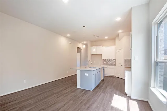 a large kitchen with a wooden floor and stainless steel appliances
