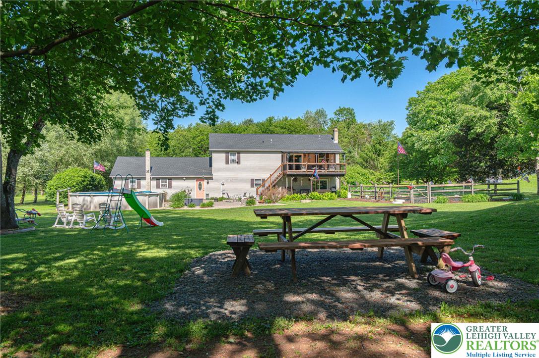 341 Lower Greenhill Road Kunkletown, PA 18058 - Photo 67 of 69 Generous green lawn with mature trees frames a home with an upper deck and a backyard pool.