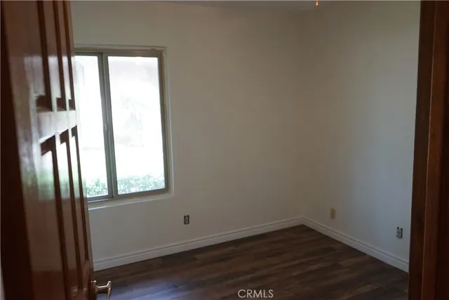 an empty room with wooden floor door and windows