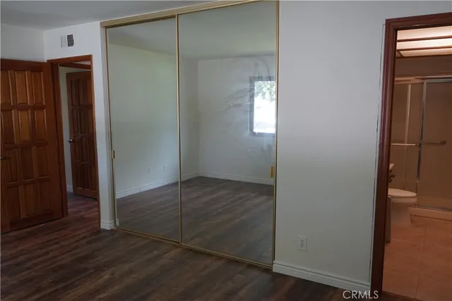 an empty room with wooden floor closet and windows