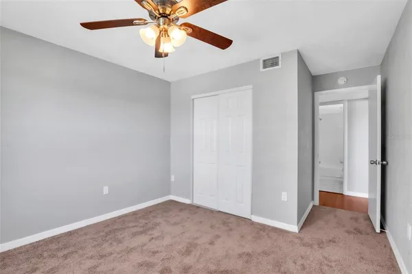 an empty room with closet and a chandelier fan