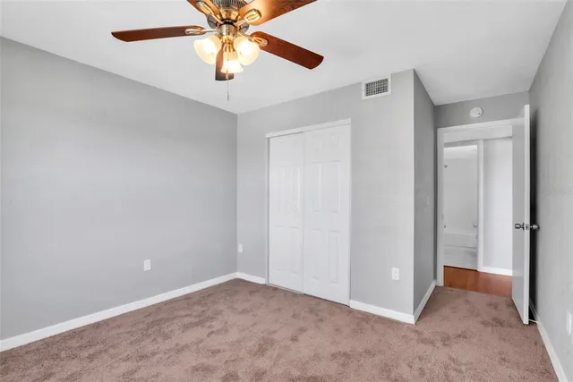 an empty room with closet and a chandelier fan