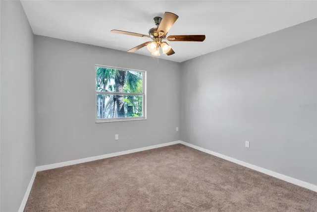 an empty room with window and ceiling fan