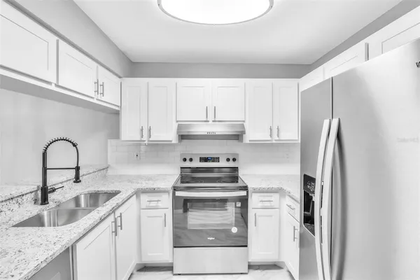 a kitchen with stainless steel appliances granite countertop a stove a refrigerator and a sink