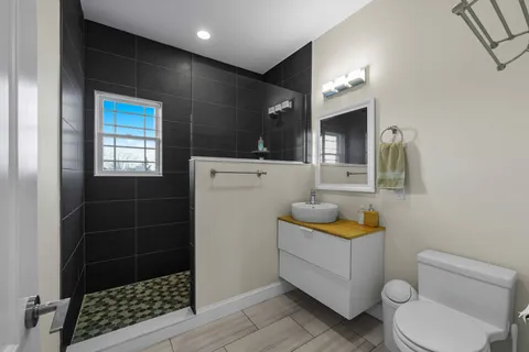 a bathroom with a sink a toilet a mirror and shower