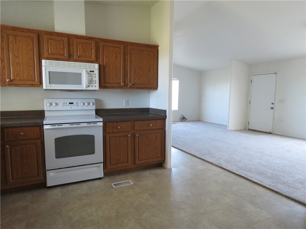785 Bacobi Road Golden Valley, AZ 86413 - Photo 23 of 35 a kitchen with granite countertop white cabinets and white appliances