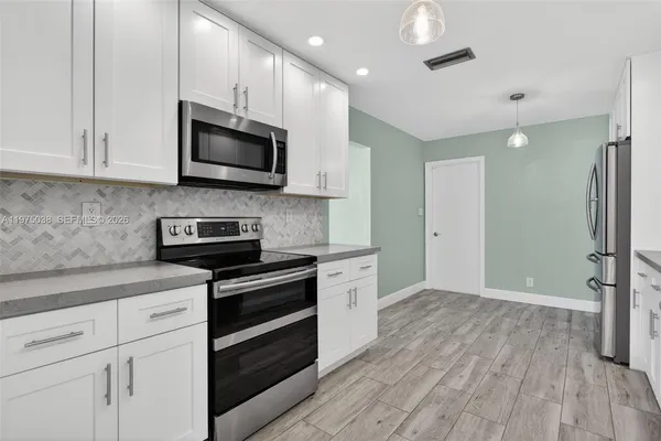a kitchen with stainless steel appliances granite countertop a stove a sink and a refrigerator