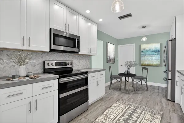 a kitchen with stainless steel appliances granite countertop a stove top oven a sink dishwasher a dining table and chairs with wooden floor