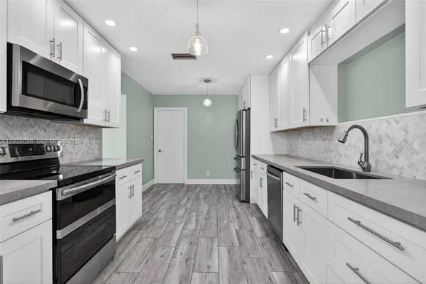 a large kitchen with stainless steel appliances granite countertop a stove a sink and a microwave
