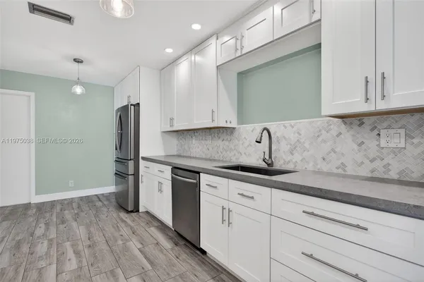 a kitchen with stainless steel appliances granite countertop a sink and a refrigerator