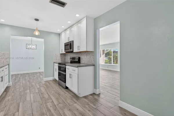 a kitchen with wooden floors and white cabinets