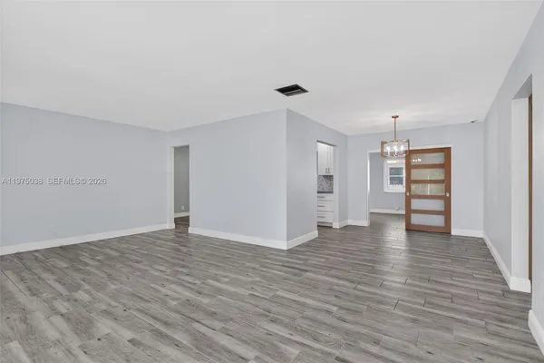 a view of an empty room with wooden floor and closet