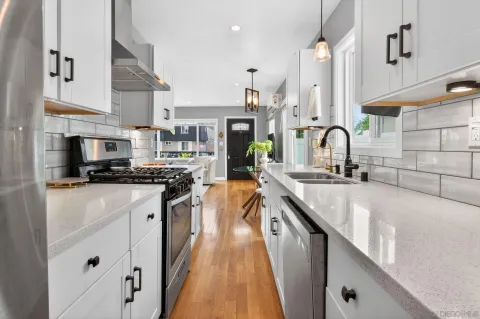 a kitchen with stainless steel appliances a sink a stove and a kitchen island with wooden floor