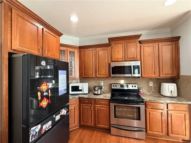 a kitchen with stainless steel appliances granite countertop a stove top oven a sink a dining table and chairs with wooden floor