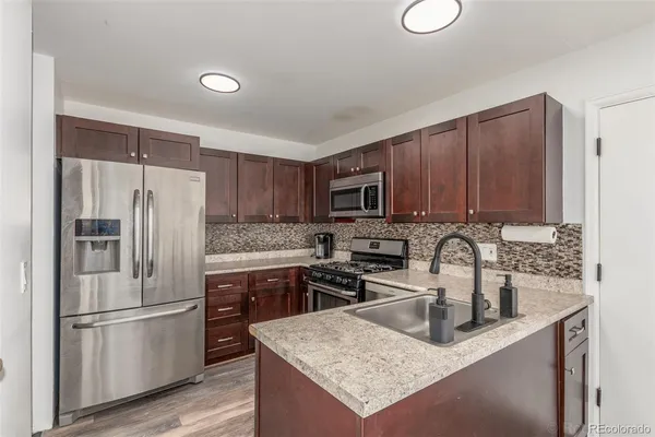 a kitchen with stainless steel appliances granite countertop a sink stove and refrigerator