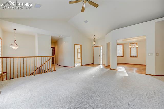 15091 Ridgefield Lane Colorado Springs, CO 80921 - Photo 6 of 35 Unfurnished room featuring ceiling fan with notable chandelier, light colored carpet, and high vaulted ceiling