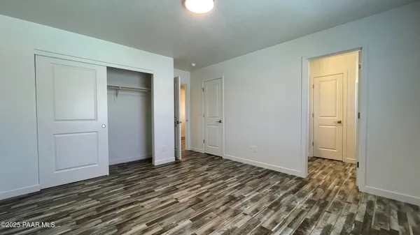 a view of an empty room with wooden floor and closet