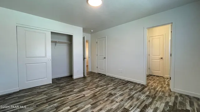 a view of an empty room with wooden floor and closet